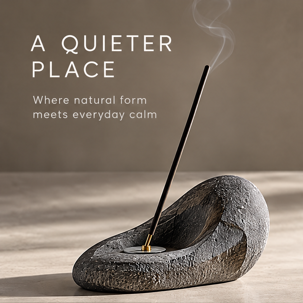 Sculptural stone incense holder with a smoking incense stick beneath A Quieter Place.