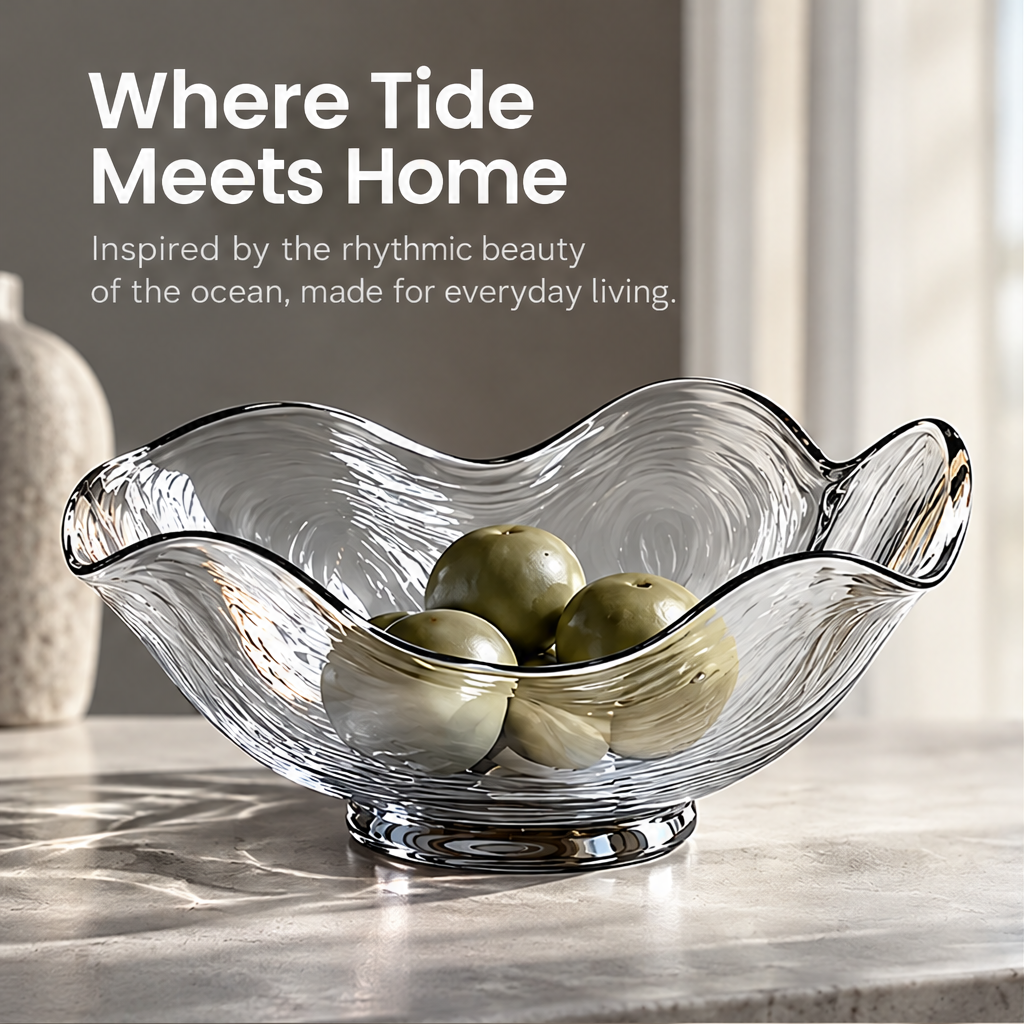 Glass centerpiece bowl holding green fruit on a sunlit table beneath Where Tide Meets Home.