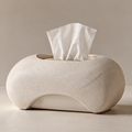 Off-white sculptural tissue box with a textured rounded body, oval top opening and curved lower arch on a plain background.