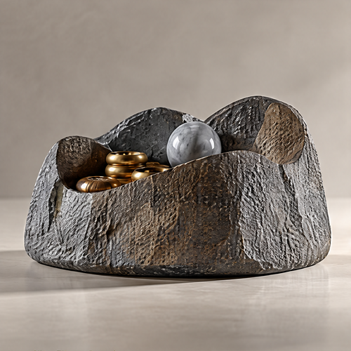 Dark textured catchall bowl with an uneven sculptural rim, holding gold-tone rings and a gray sphere on a plain background.