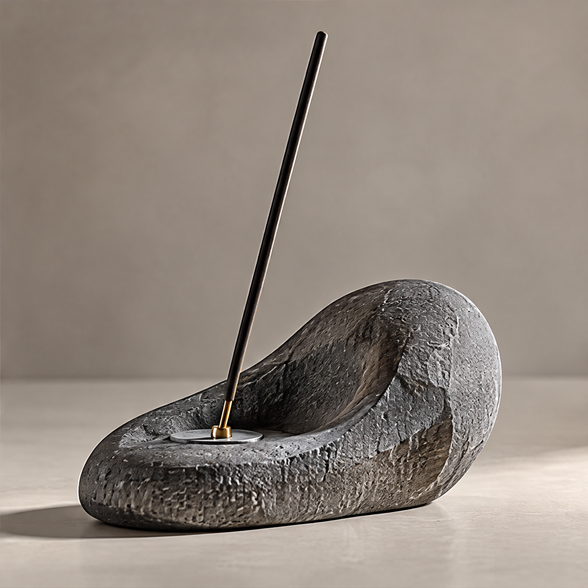 Dark textured stone incense holder with an organic curved profile, silver-tone disc and gold-tone socket on a plain background.